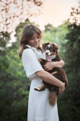 photo d'une femme avec son chiot berger américain miniature en foret en essonne